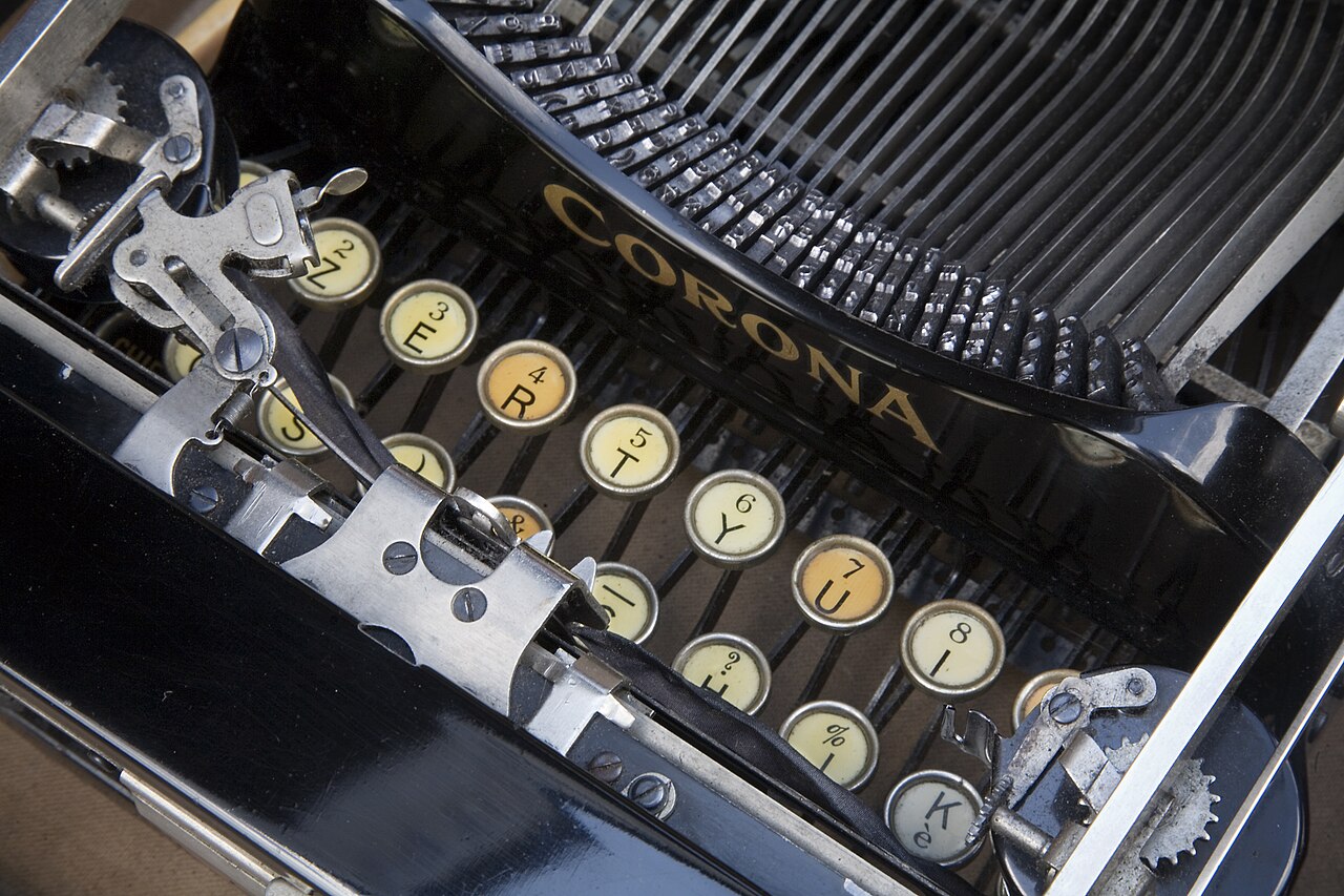 A vintage Corona folding typewriter displayed on a surface, with its compact form visible.