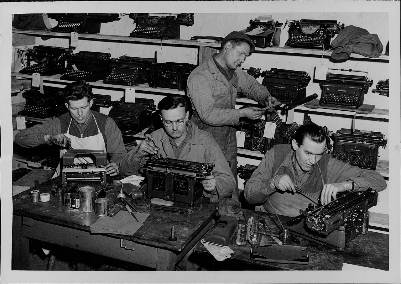 Hands at a workbench repairing typewriter mechanisms, illustrating careful bench practice.