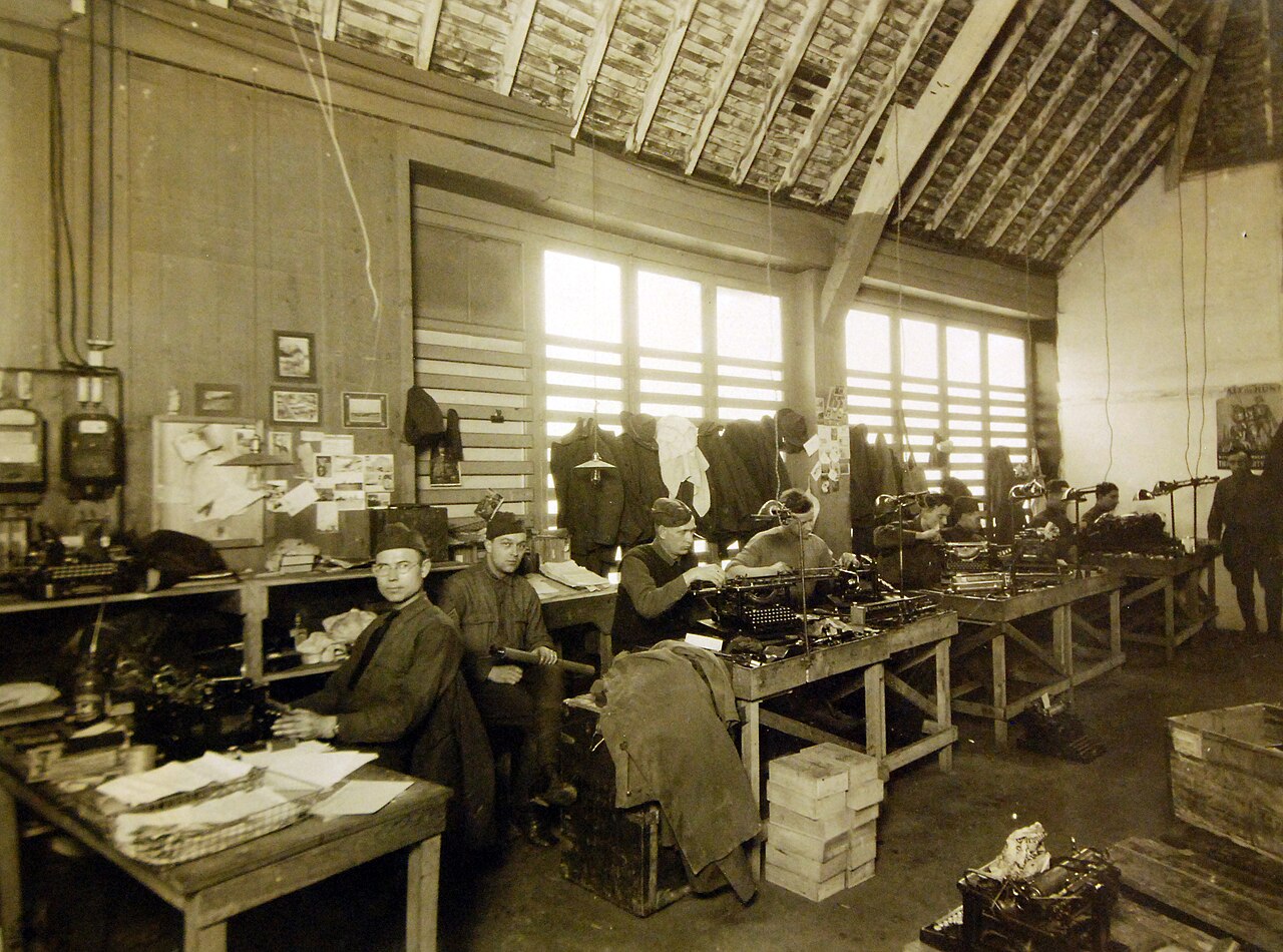 Soldiers working at typewriter repair benches in a historical repair shop, 1919.